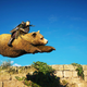 Eivor riding a bear as it leaps over a small wall.